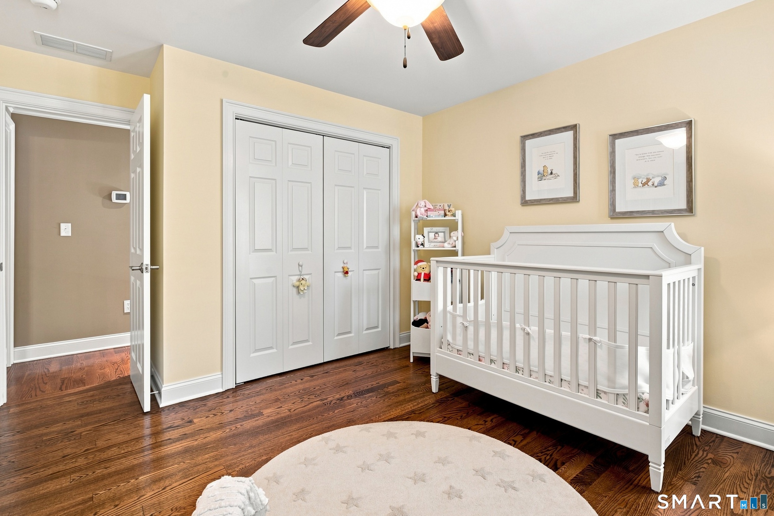 Nursery with a white crib, framed animal prints, and a round star-patterned rug.