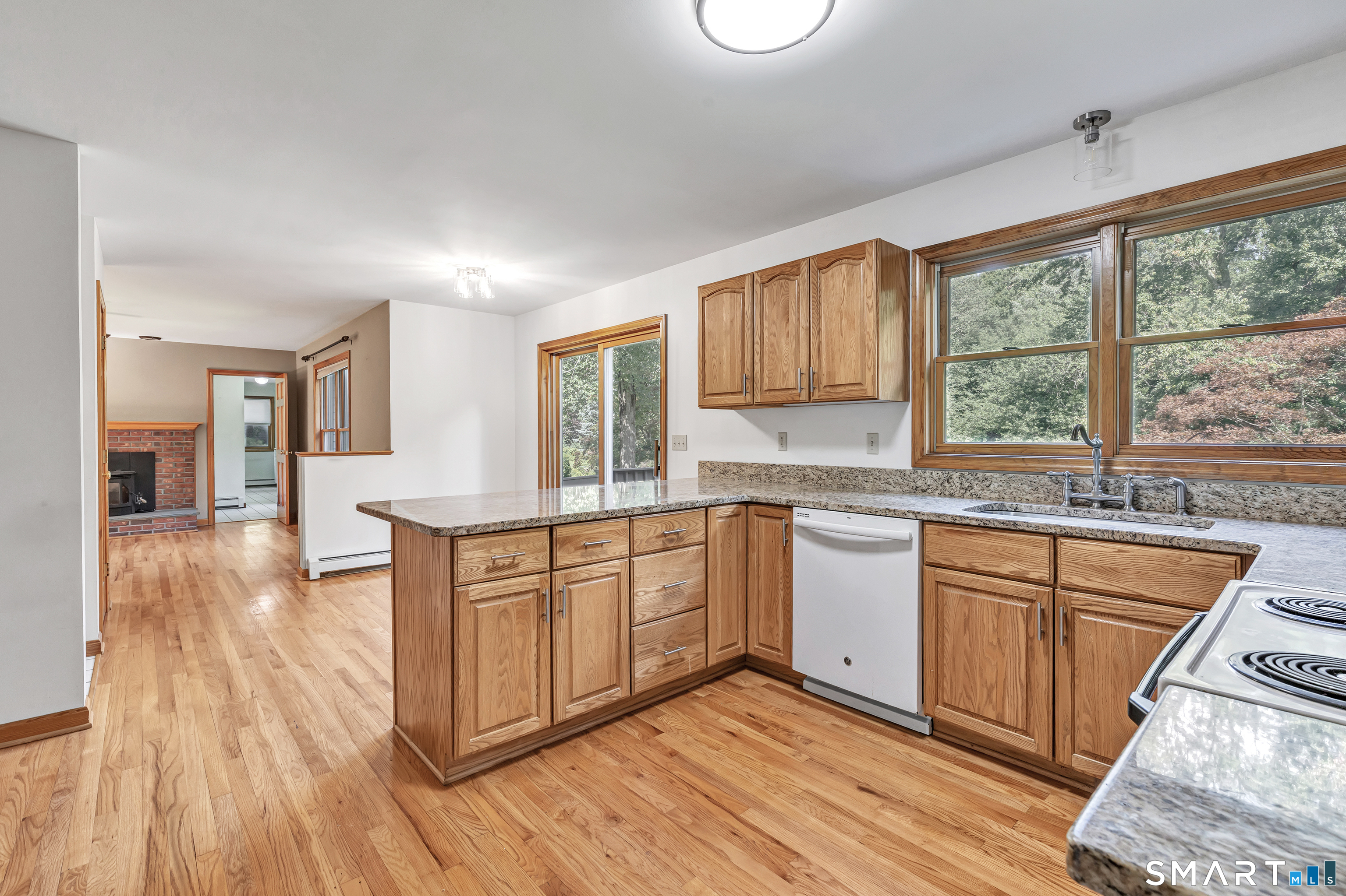 Kitchen with wood cabinets, granite counters, a central island, hardwood floors, and large windows.
