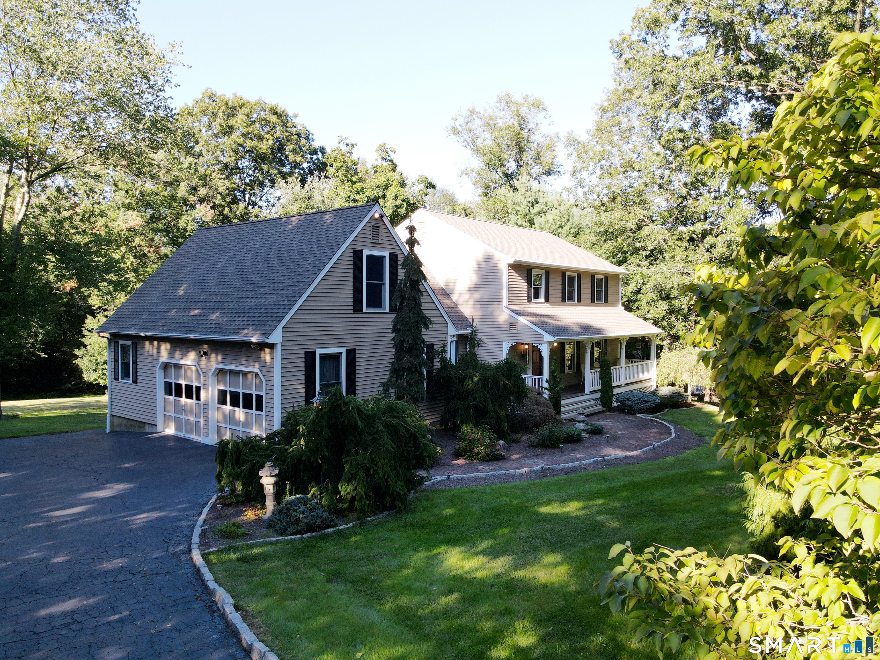Gray two-story home with attached garage, covered porch, and landscaped front yard.