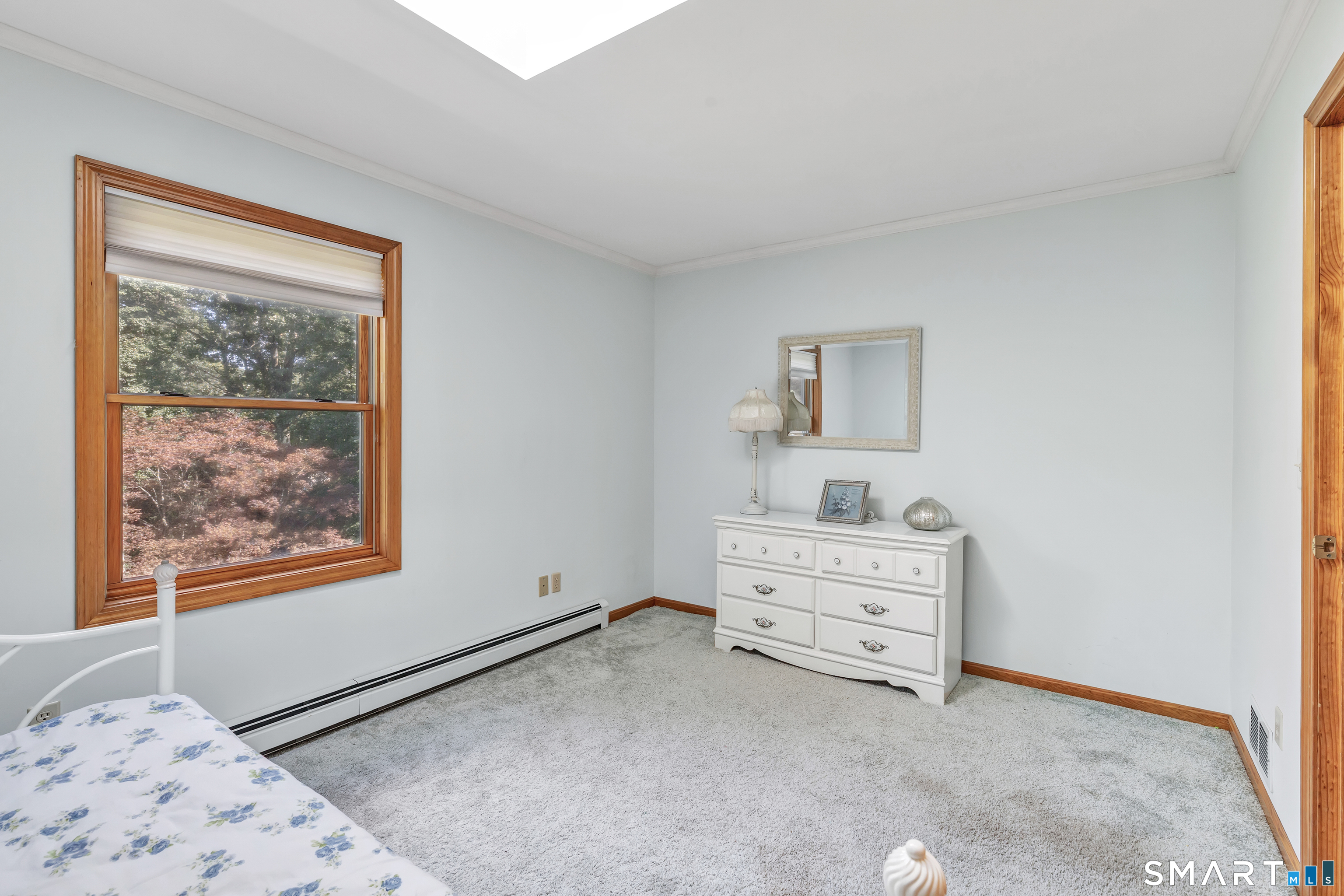 Bedroom with a large wood-trimmed window and white dresser.