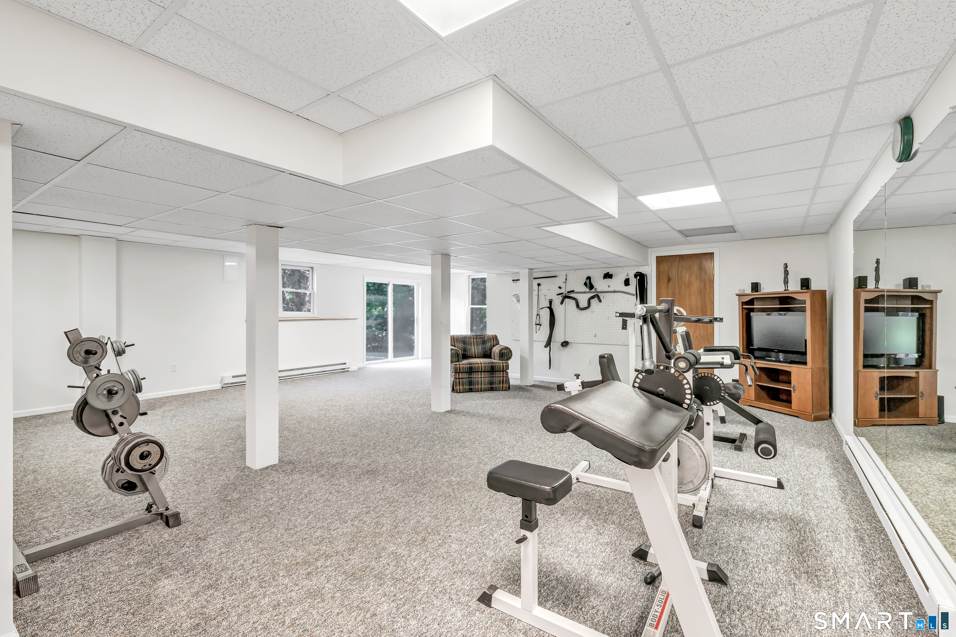 Basement gym with weight equipment, a multi-station exercise machine, and a mirrored wall.