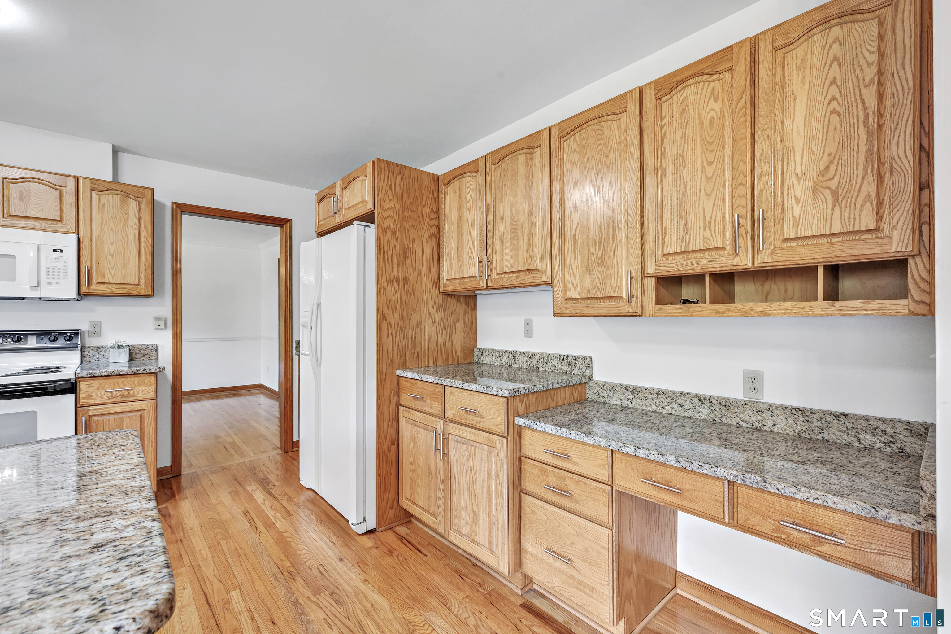 Kitchen with honey-colored wood cabinets, granite countertops, and wood flooring.