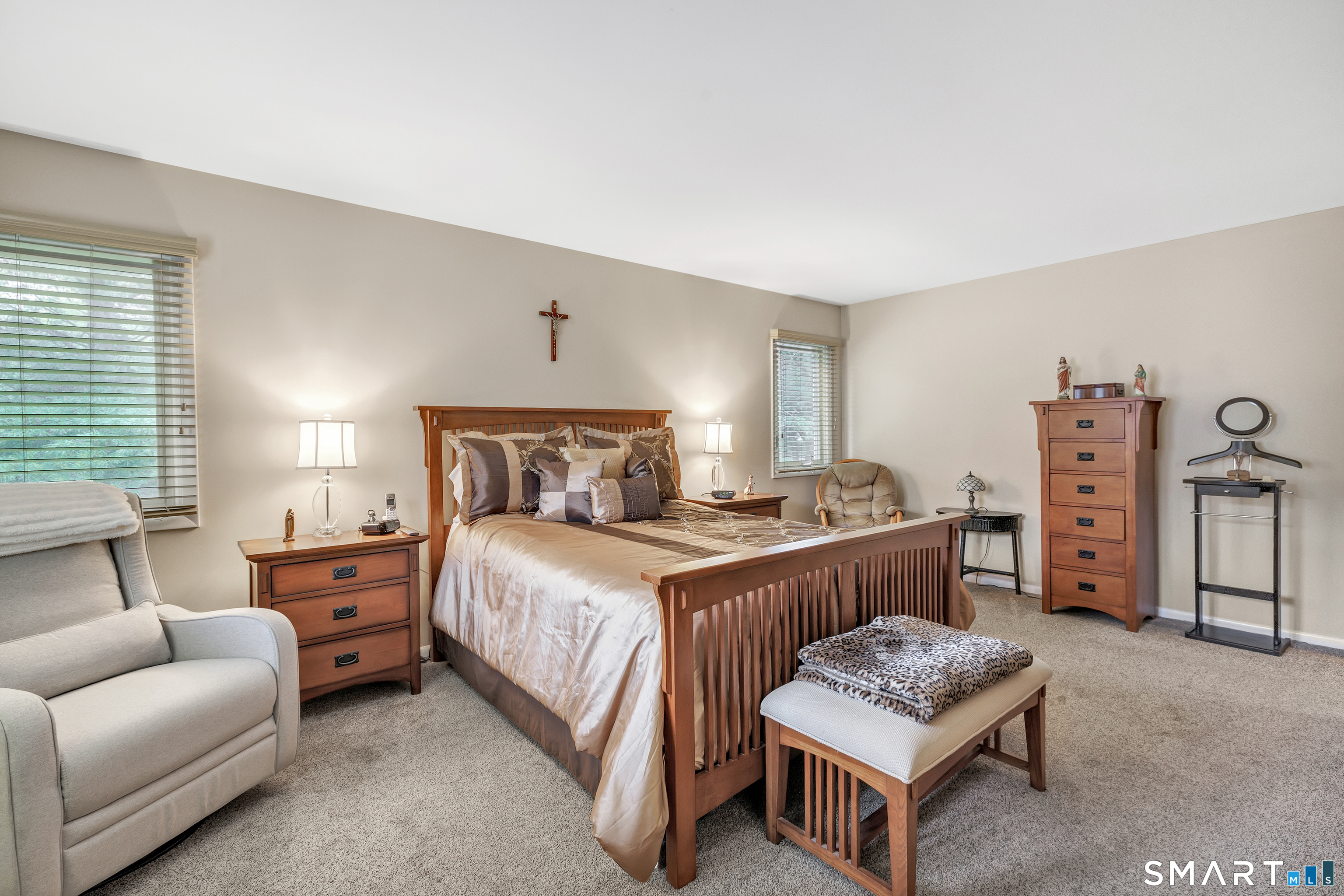 Furnished bedroom with a wooden four-poster bed, matching dressers, and a crucifix above the headboard.