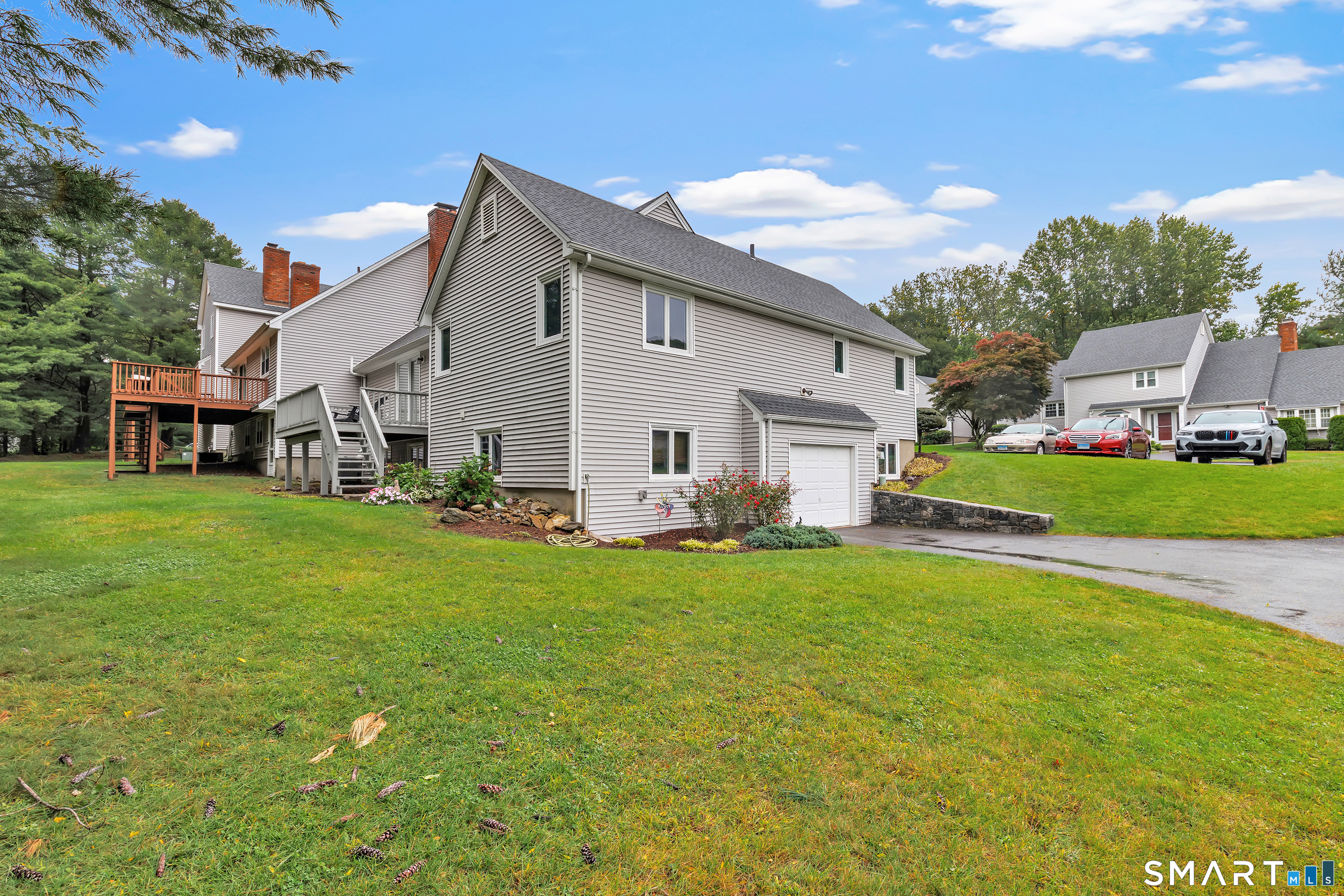 Gray-sided home with an attached garage, raised deck, and landscaped lawn.
