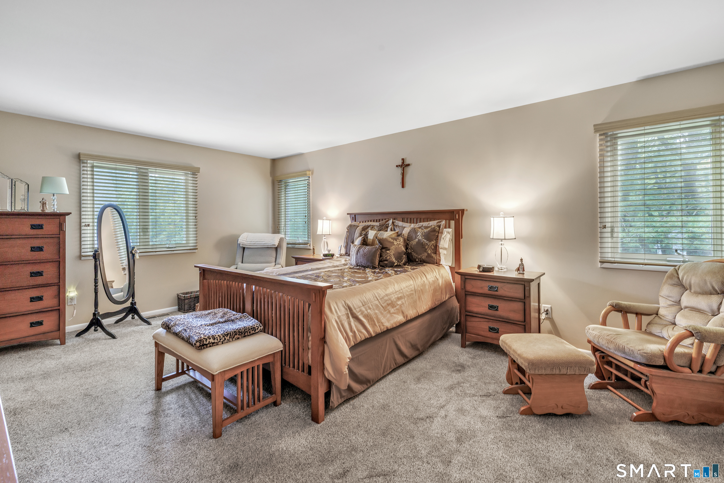 Furnished bedroom with a wooden bed, matching furniture, and a crucifix above the headboard.