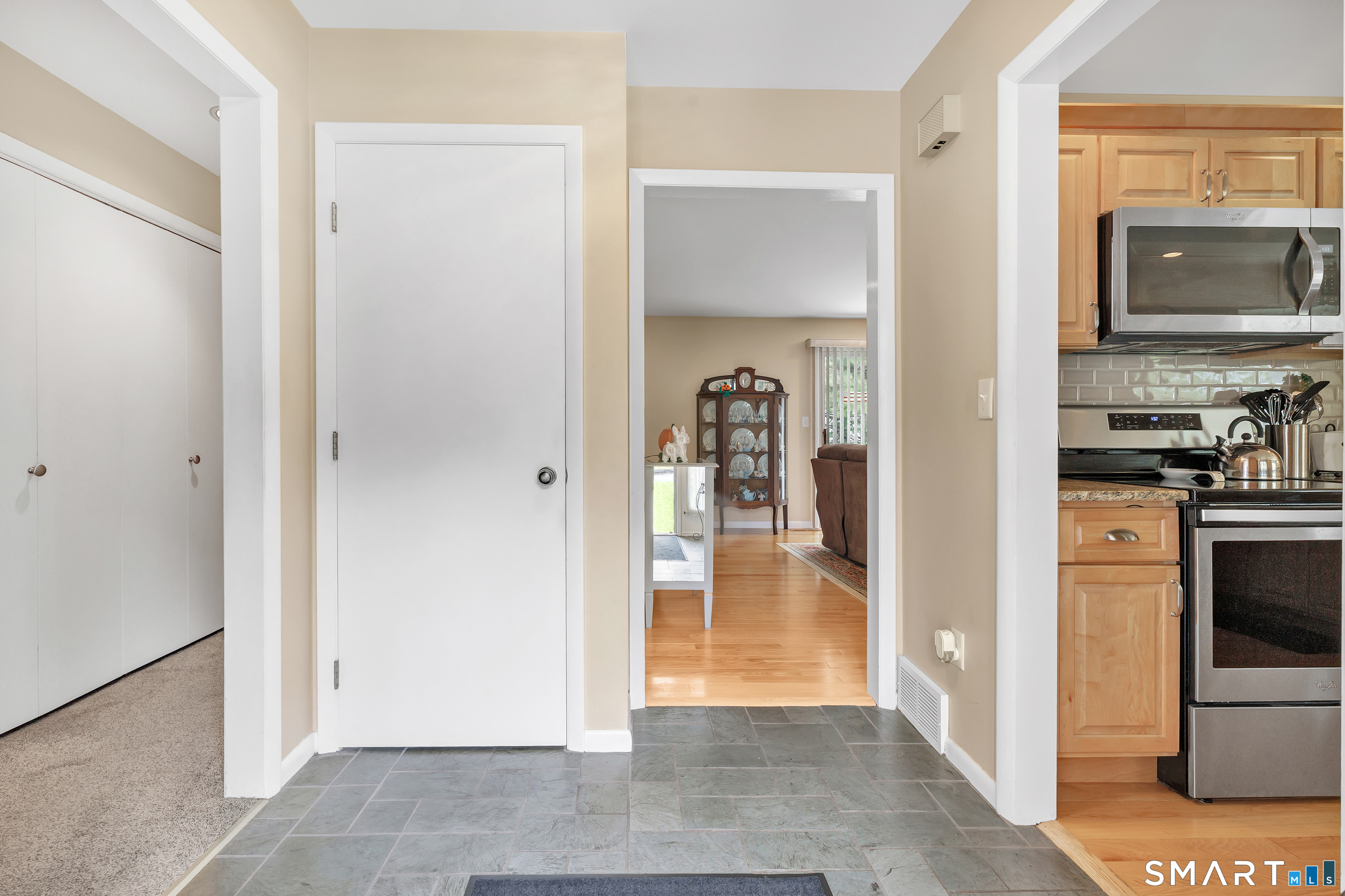 Entryway with slate tile flooring, a white closet, and views into the living room and kitchen.
