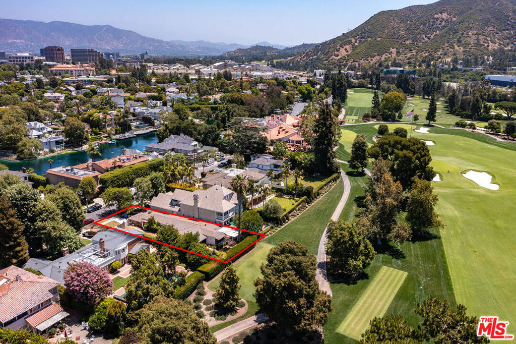 Aerial view of a red-outlined property beside a golf course and lake.