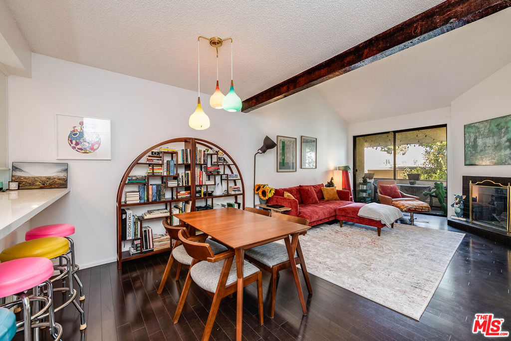 Living and dining room with a red sectional, arched bookshelf, exposed beam, and balcony doors.