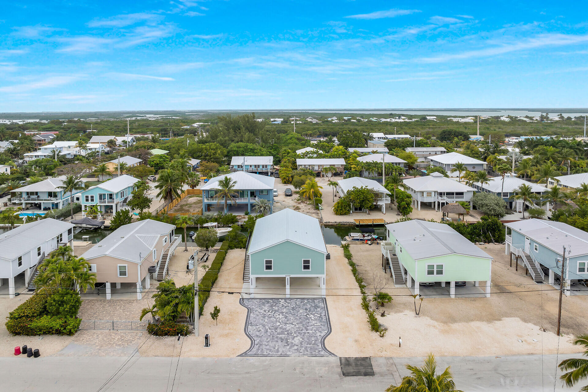 Aerial view of the turquoise raised home marked 22737, with a patterned driveway and water visible in the distance.