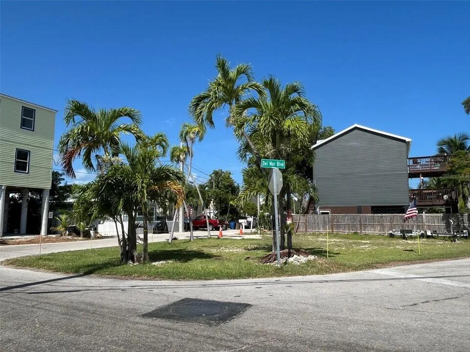 Grassy corner lot with palm trees and neighboring homes beside a Del Mar Blvd street sign.