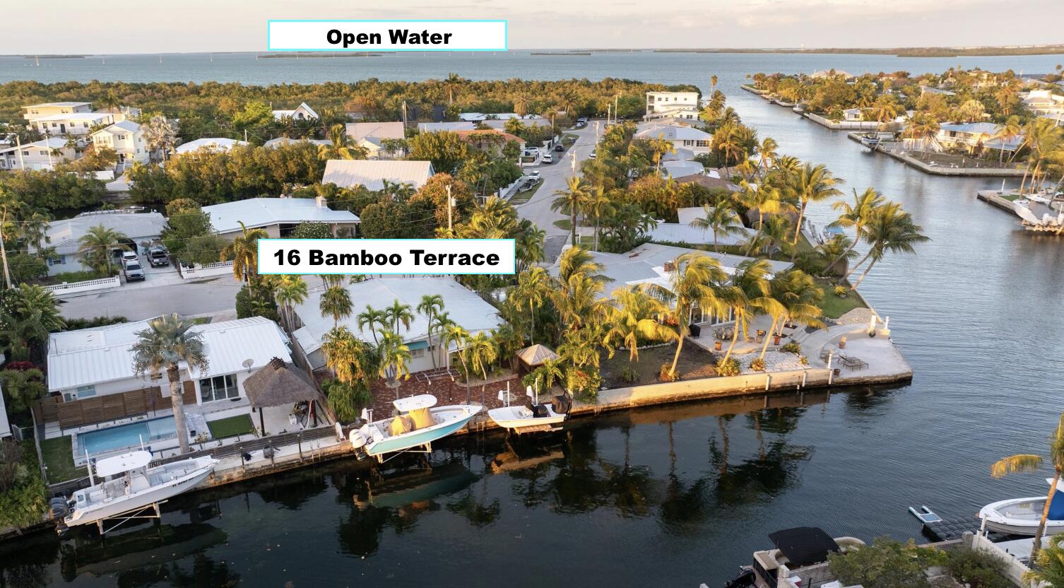 Aerial view of 16 Bamboo Terrace beside a canal, with boats, waterfront homes, and open water.