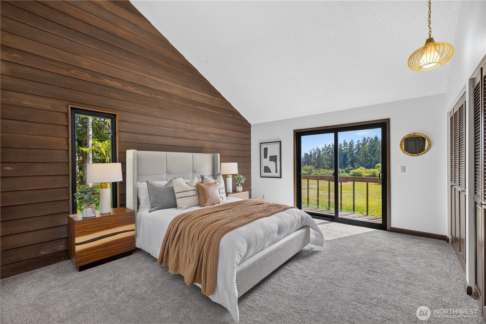 Staged bedroom with a wood accent wall and sliding doors opening to a balcony.