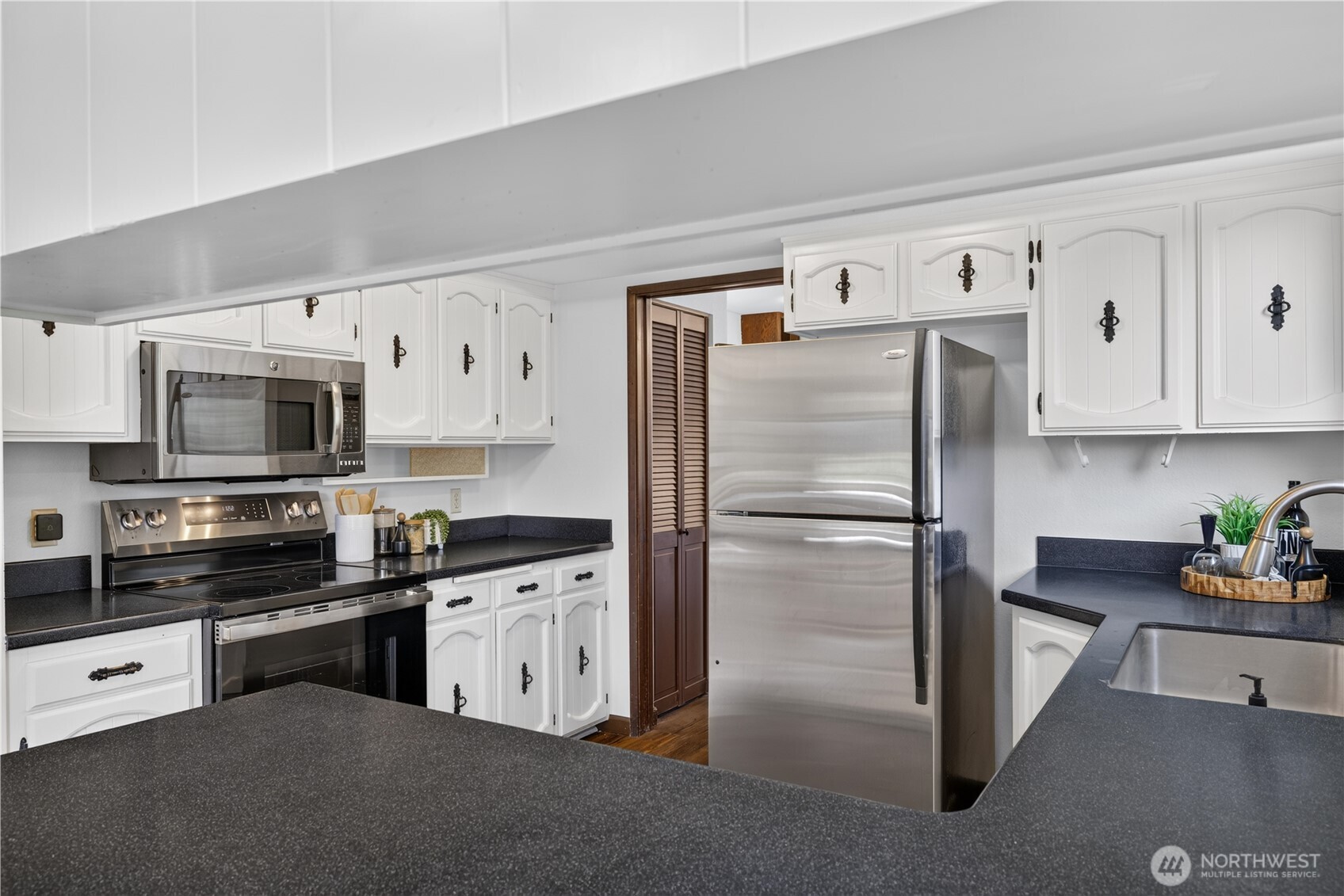 Kitchen with white cabinets, stainless steel appliances, and dark countertops.