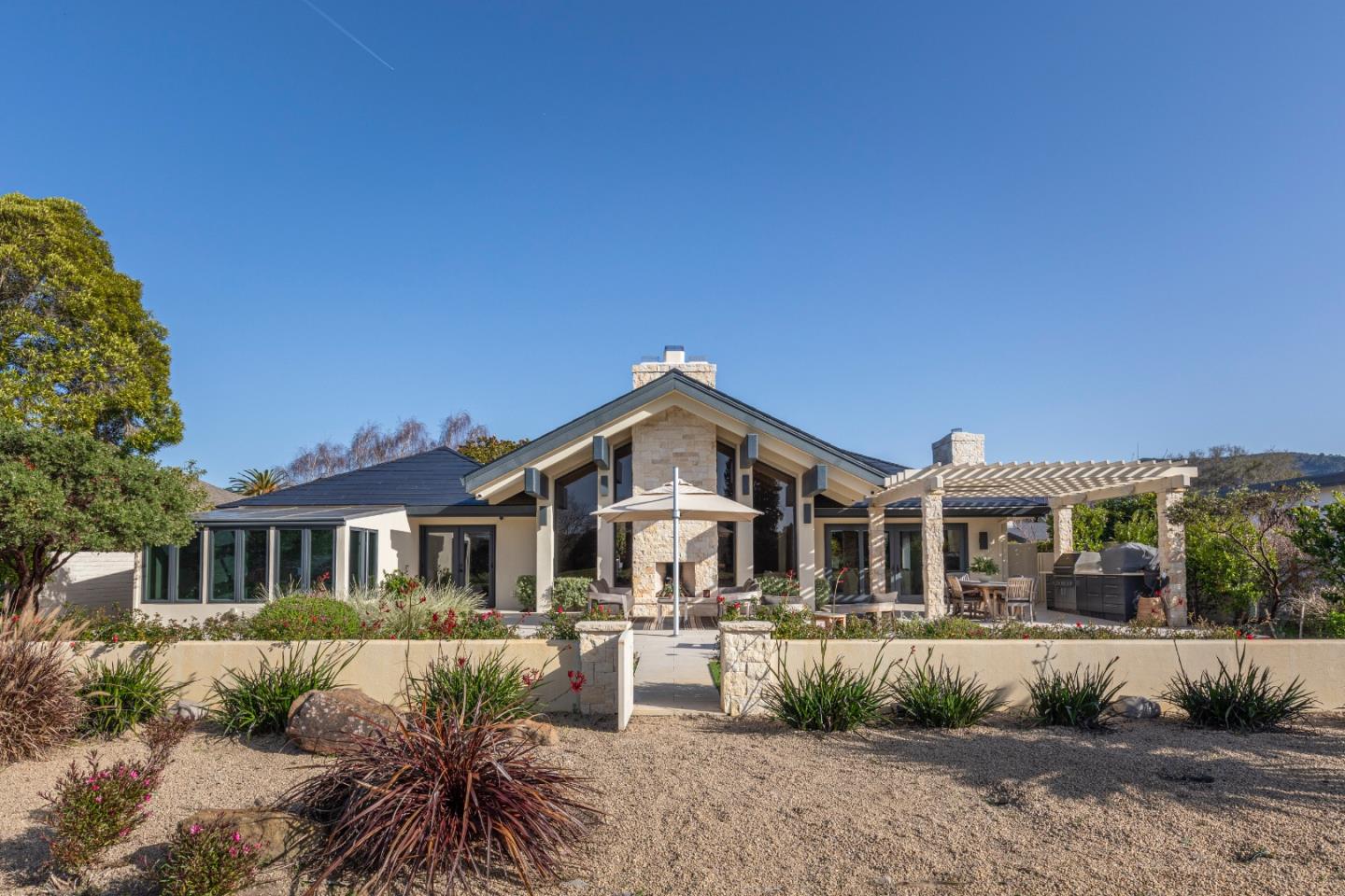 Modern stone-accented home with a covered patio, pergola, and drought-tolerant landscaping.