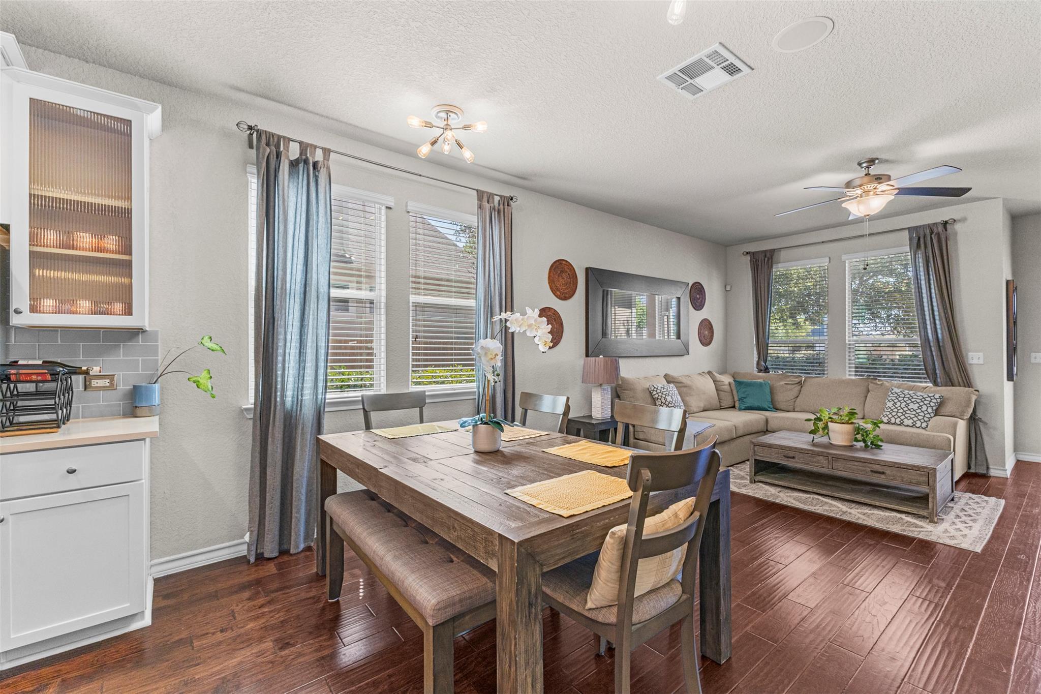 Open-plan dining and living room with a rustic wood table and beige sectional sofa.