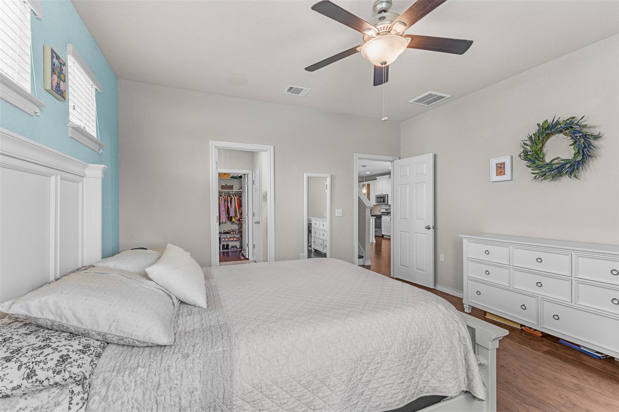 Bedroom with a white bed, turquoise accent wall, and open walk-in closet.