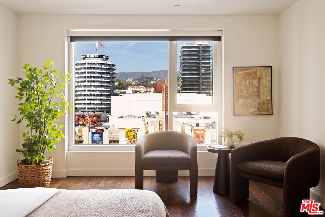 Bedroom sitting area with a large window overlooking Hollywood buildings and hills.