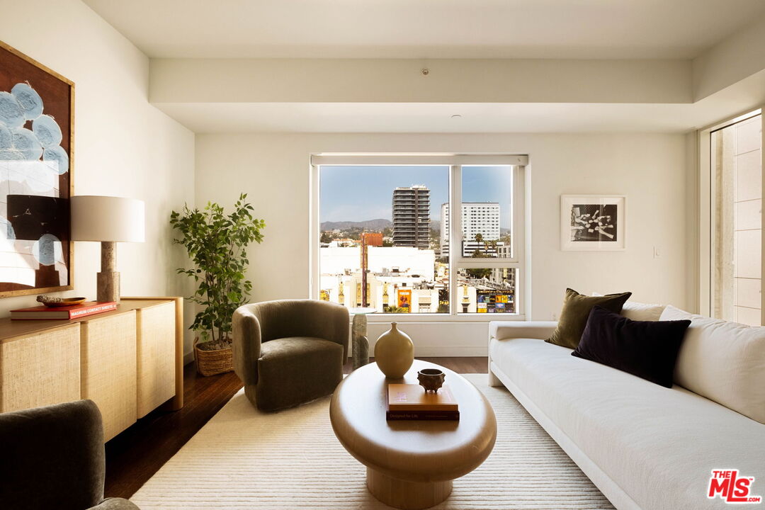 Living room with a white sofa and city views through a large window.