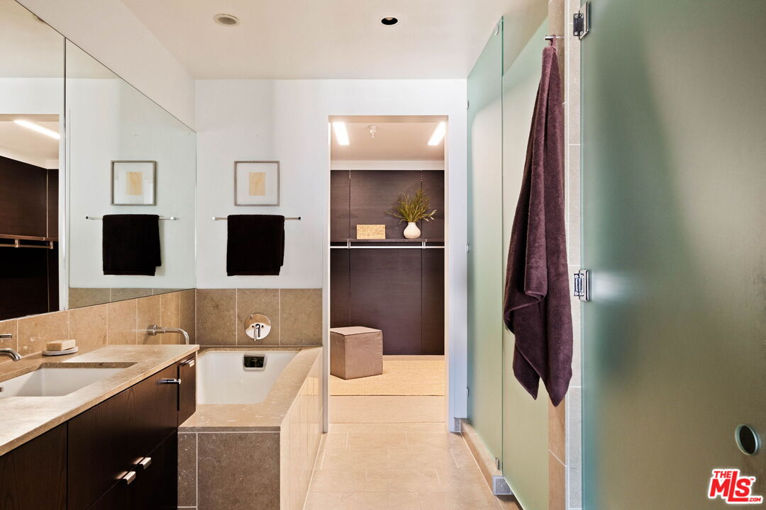 Bathroom with a stone tub, dark wood vanity, and frosted glass shower enclosure.