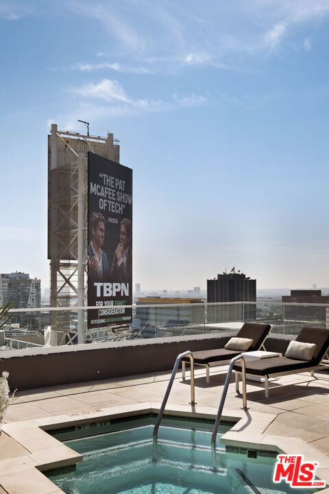 Rooftop pool with lounge chairs and a billboard above the surrounding city buildings.