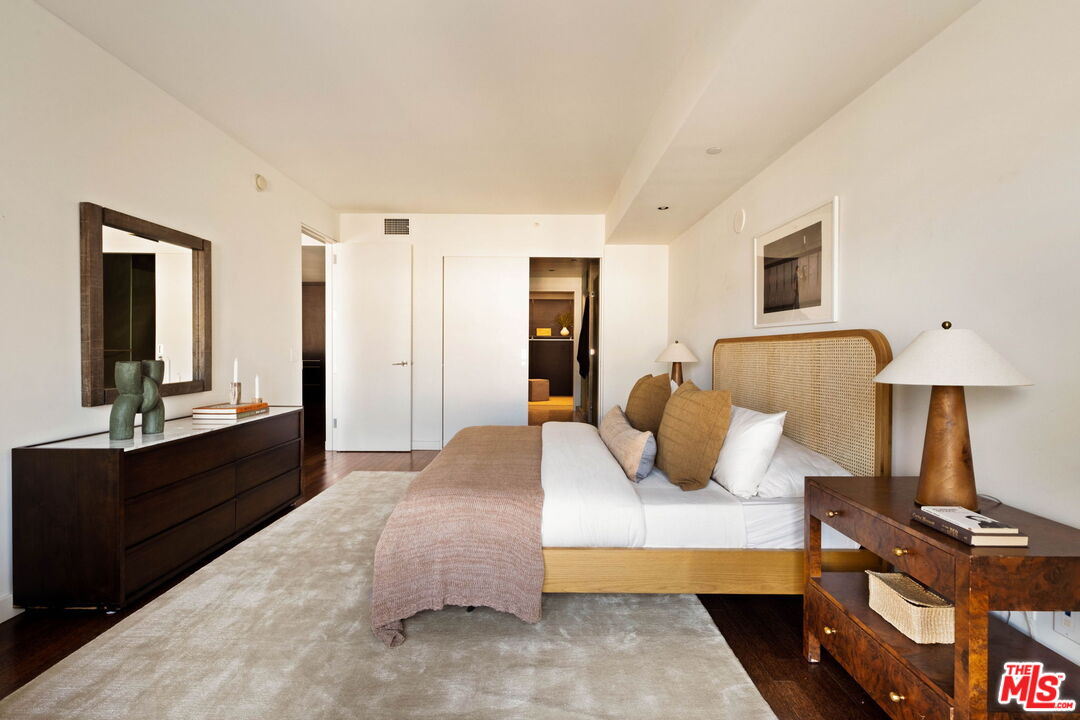 Bedroom with a cane headboard, white bedding, blush throw, and dark wood furniture.