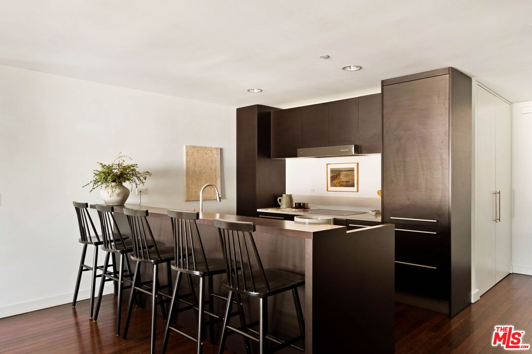Modern kitchen with dark cabinetry, a long island, and four bar stools.
