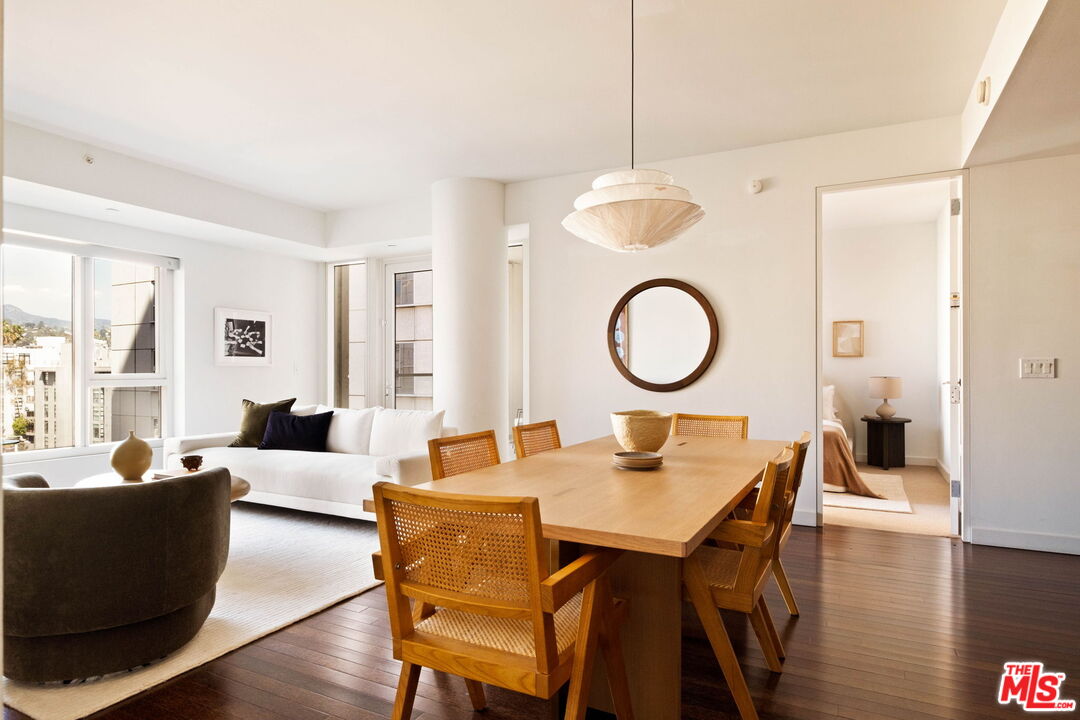 Open-plan living and dining area with a wooden table, cane-back chairs, and large windows.
