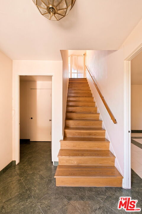Entry hall with a broad wooden staircase and dark green tile flooring.