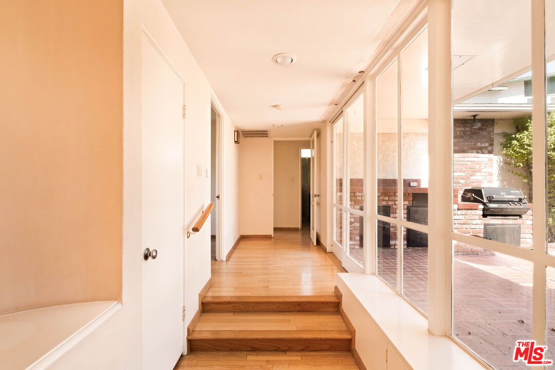 Bright hallway with hardwood steps and glass doors overlooking a brick patio.