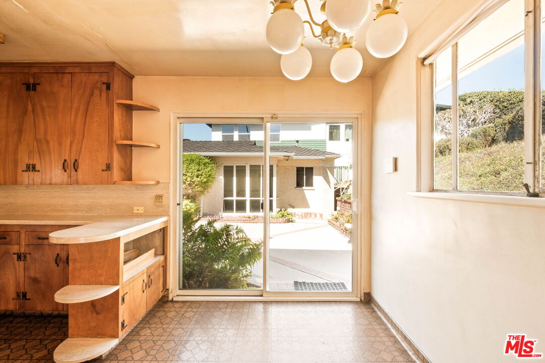 Kitchen with warm wood cabinets and a curved counter beside sliding glass doors to a patio.