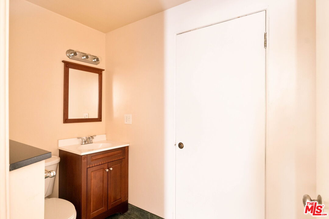 Bathroom with a dark wood vanity, white sink, framed mirror, and large white door.