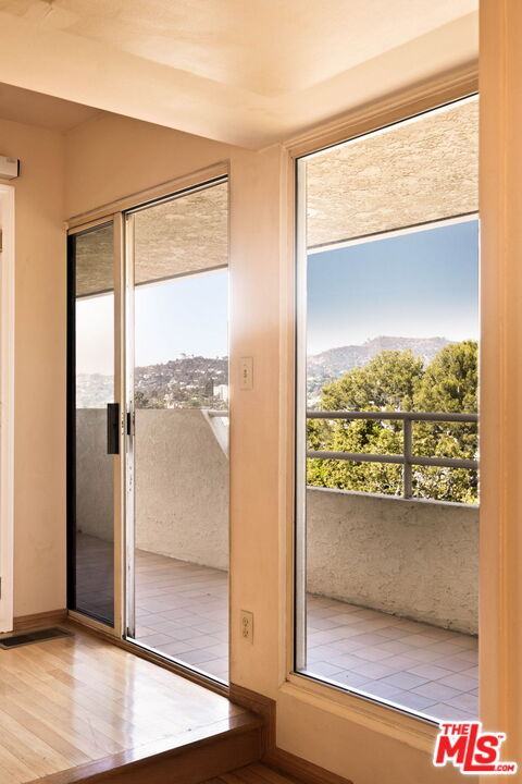 Room with hardwood floors and sliding glass doors opening to a balcony with hillside views.