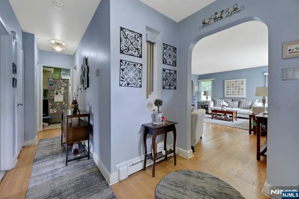 Furnished entry hall with hardwood floors and an arched opening to a living room.