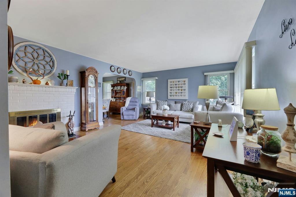 Furnished living room with a white brick fireplace, blue walls, and hardwood floors.
