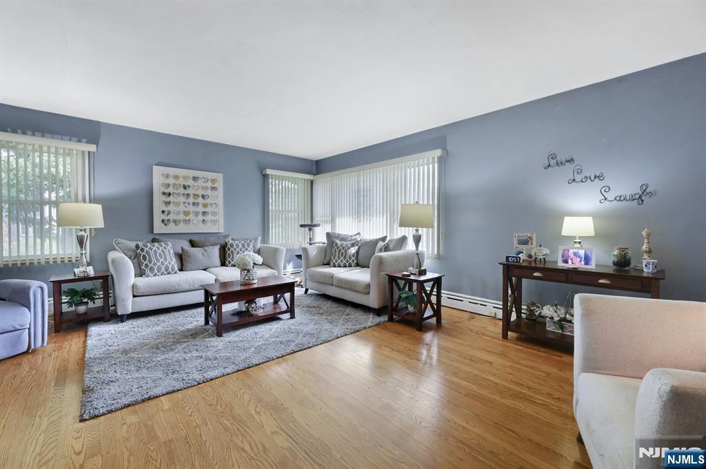 Furnished living room with gray seating, hardwood floors, and wide corner windows.