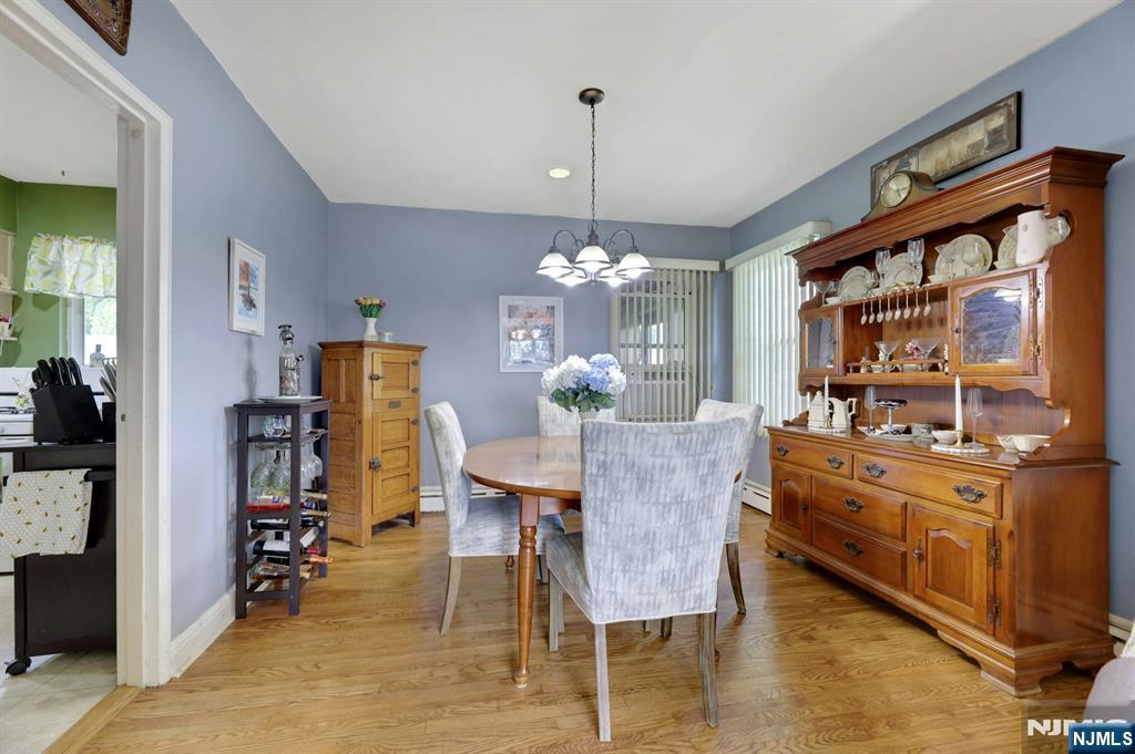 Dining room with a round table, upholstered chairs, hardwood floors, and a large wooden china cabinet.
