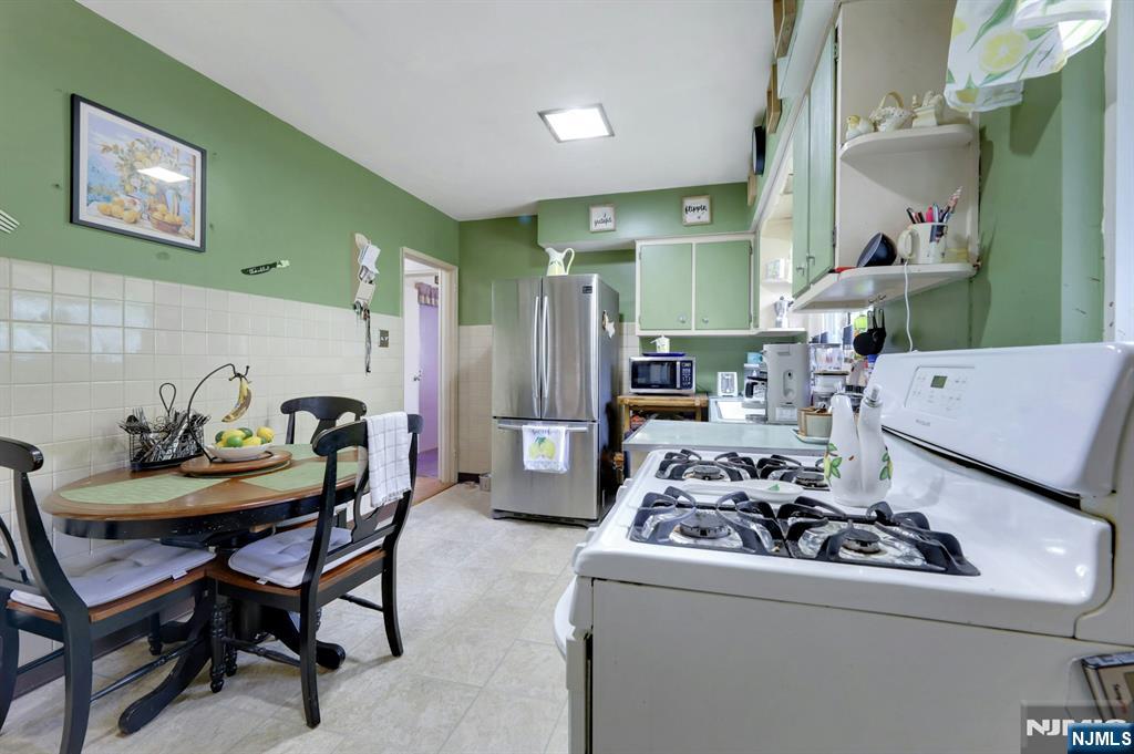 Kitchen with green walls, stainless-steel refrigerator, gas range, and a round dining table.