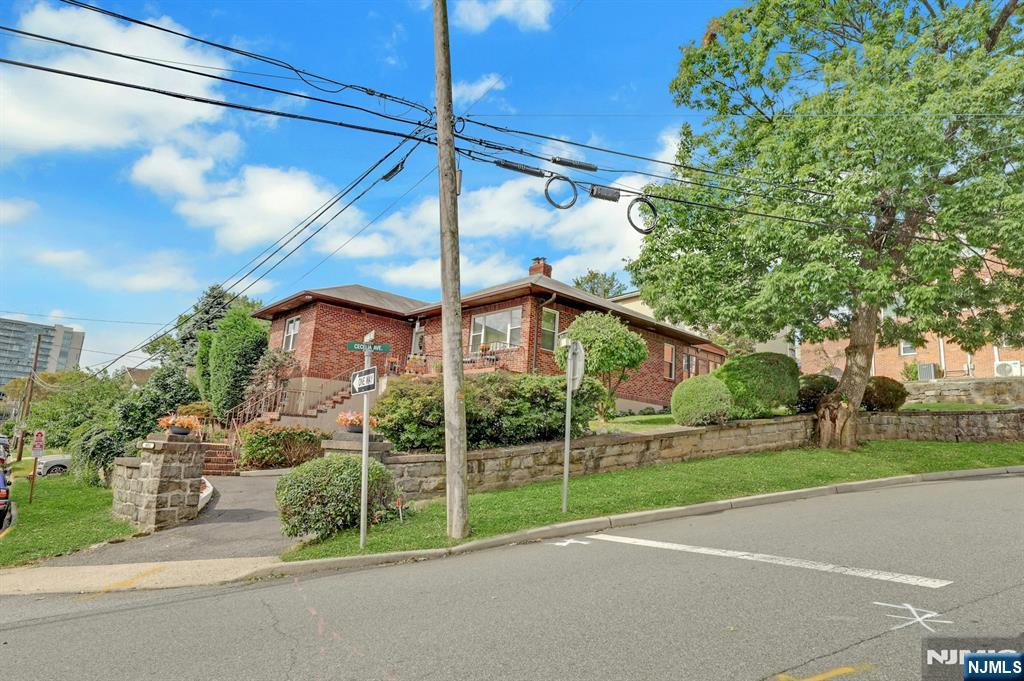 Red-brick building on a raised, landscaped lot beside the road.