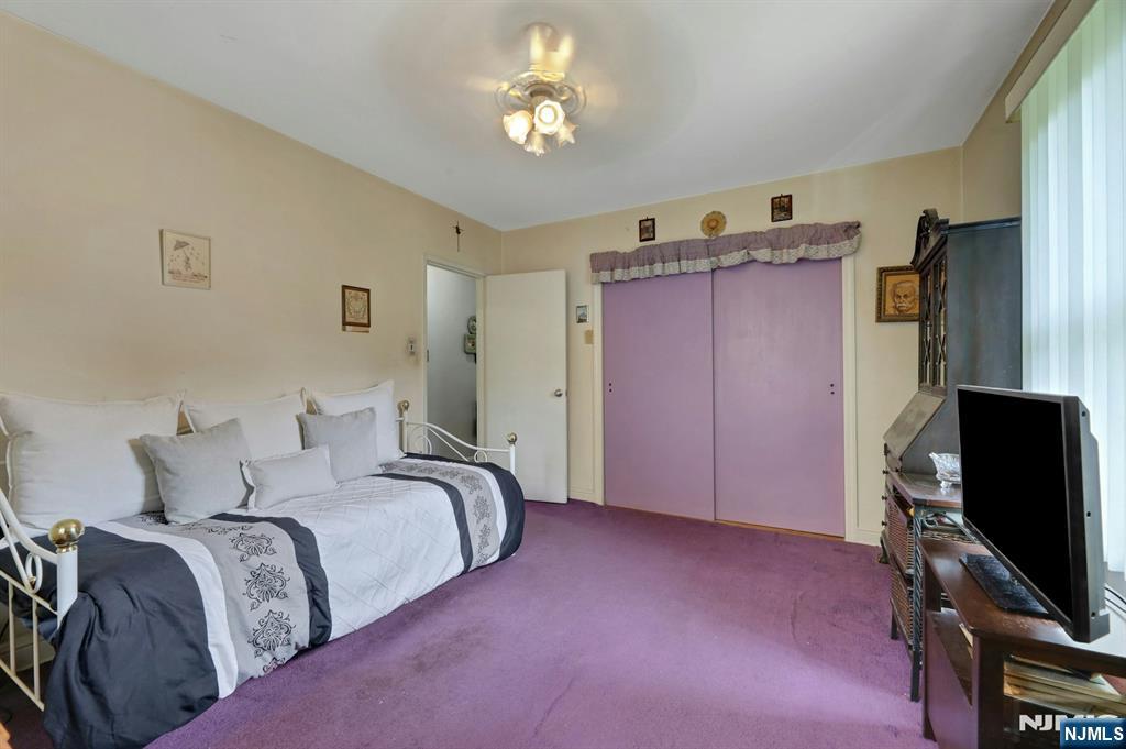 Bedroom with a white metal bed, purple carpet, and purple sliding closet doors.