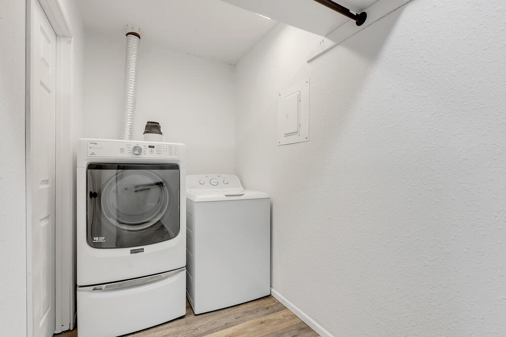 Laundry room with a front-loading dryer beside a top-loading washer and wood-look flooring.