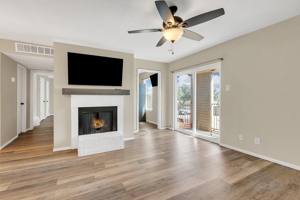 Living room with a white fireplace, mounted television, and sliding glass doors to a balcony.