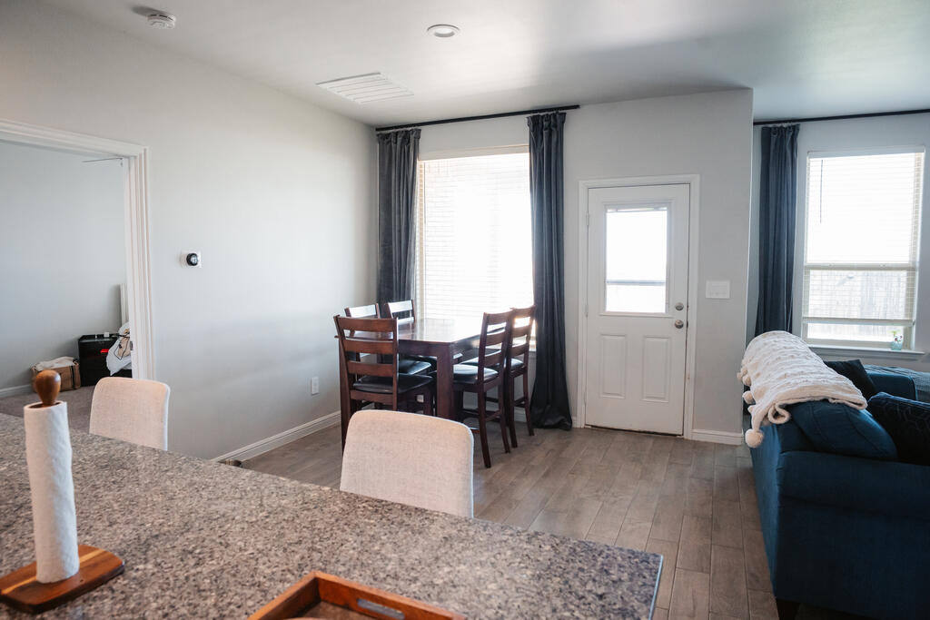Open-plan living and dining area with a granite kitchen counter, dark wood table, and blue sofa.