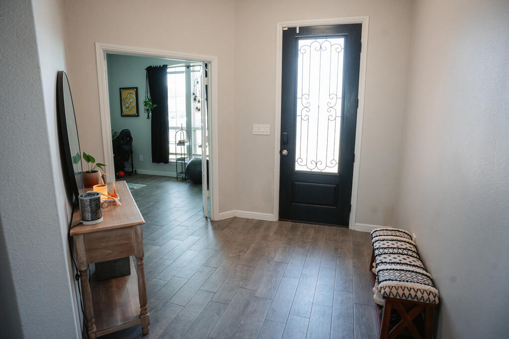 Entryway with gray tile floors, a black decorative-glass front door, and a console table.