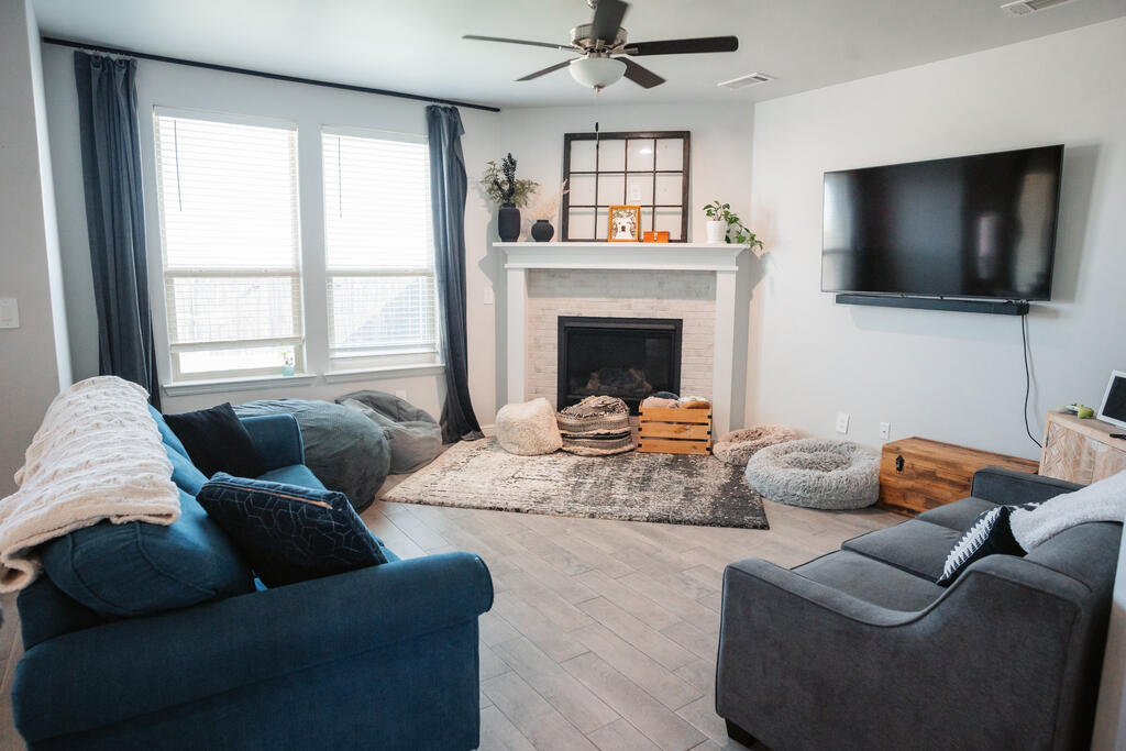 Living room with a white fireplace, wall-mounted TV, and blue and gray sofas.