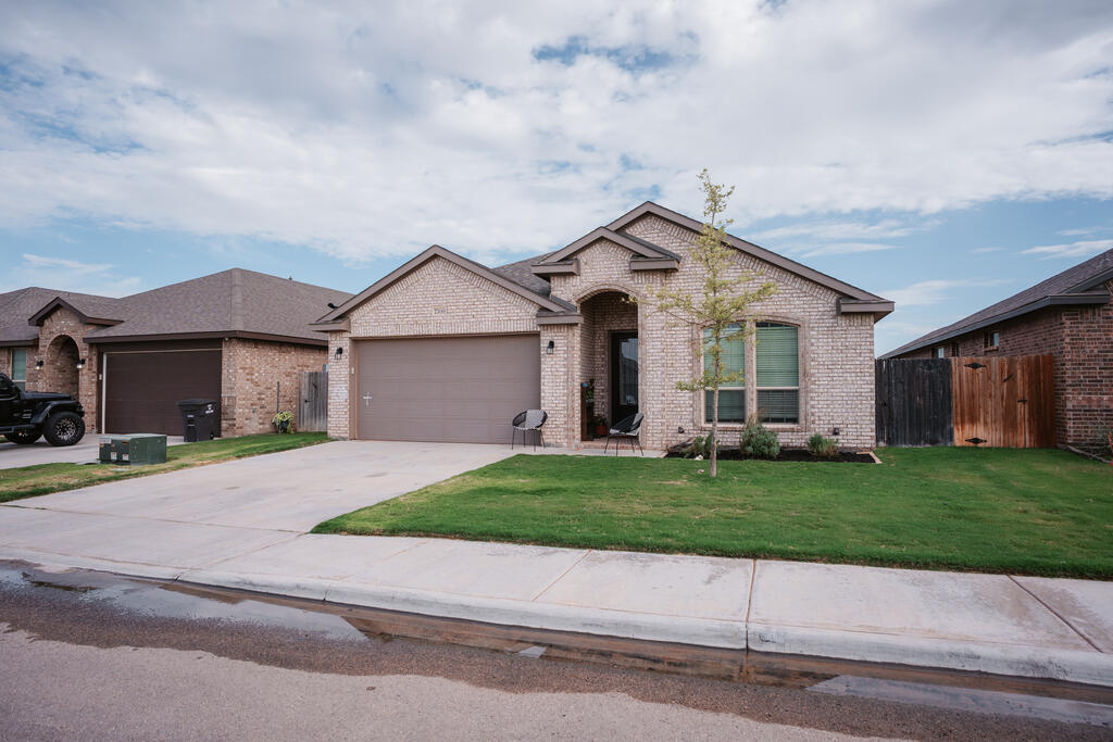 Light brick house with an attached two-car garage, covered entry, and front lawn.