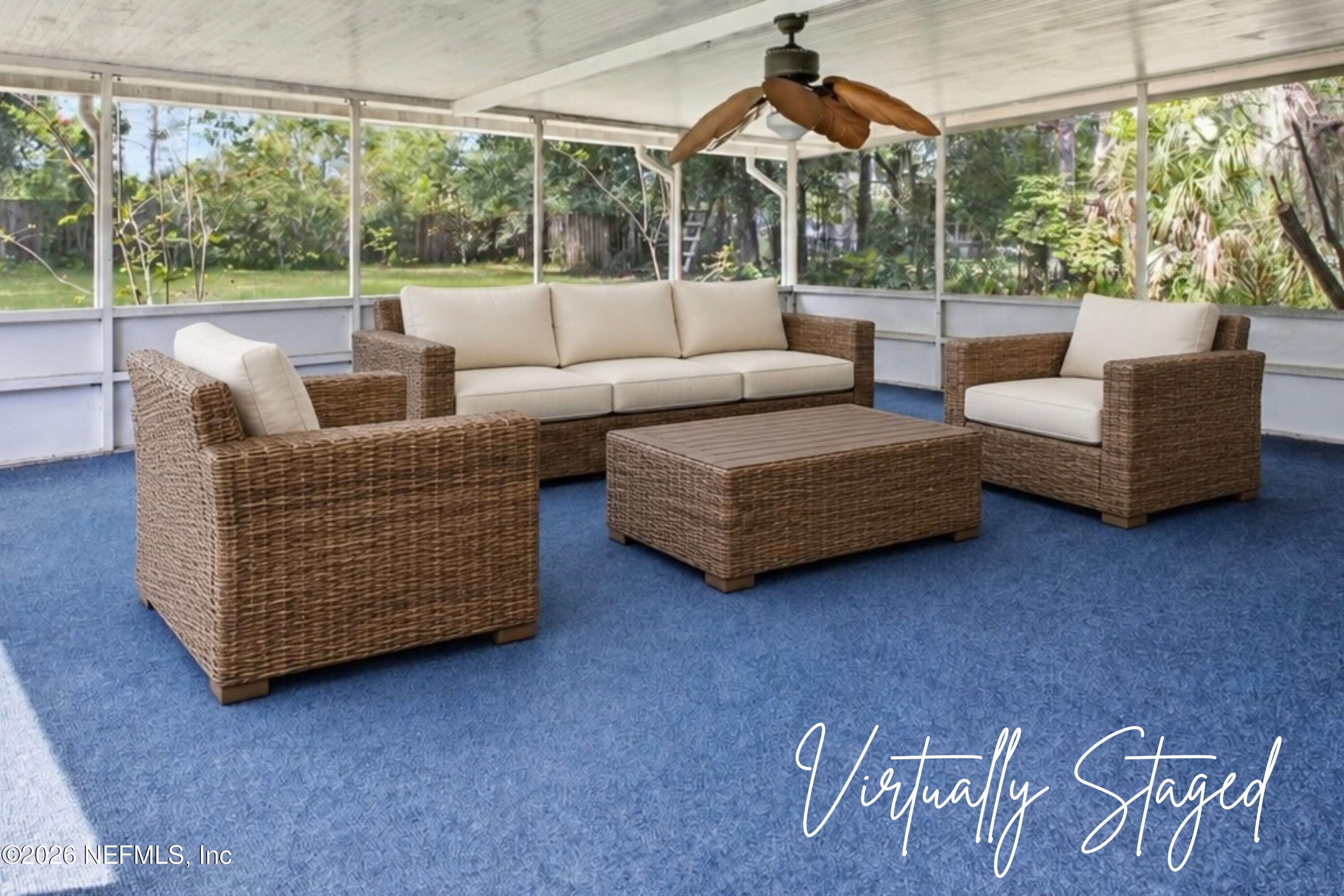 Screened porch with wicker seating, cream cushions, blue carpet, and a ceiling fan.