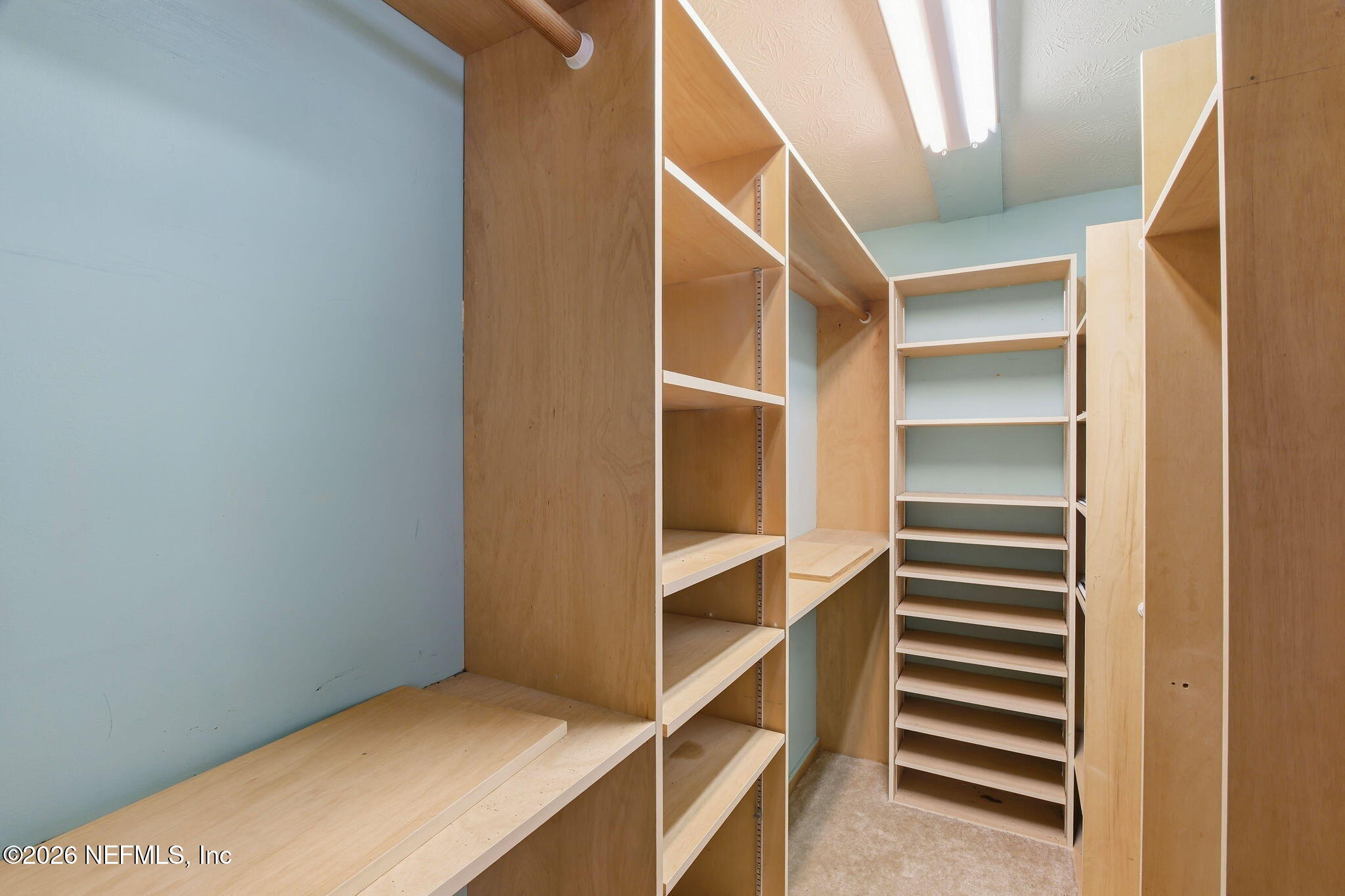Walk-in closet with extensive built-in wood shelving and a hanging rod.