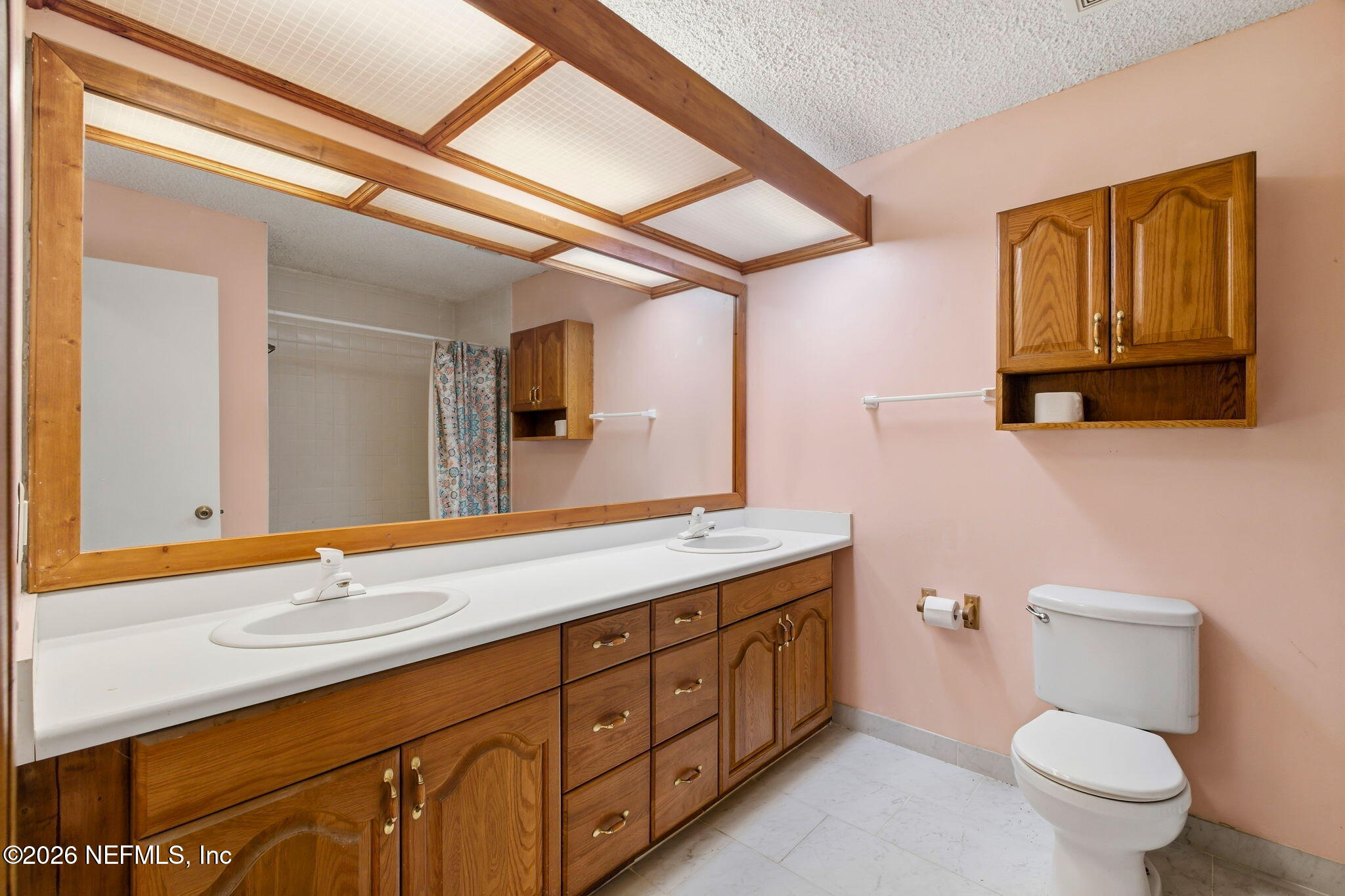 Bathroom with a double-sink wood vanity, large framed mirror, and toilet.