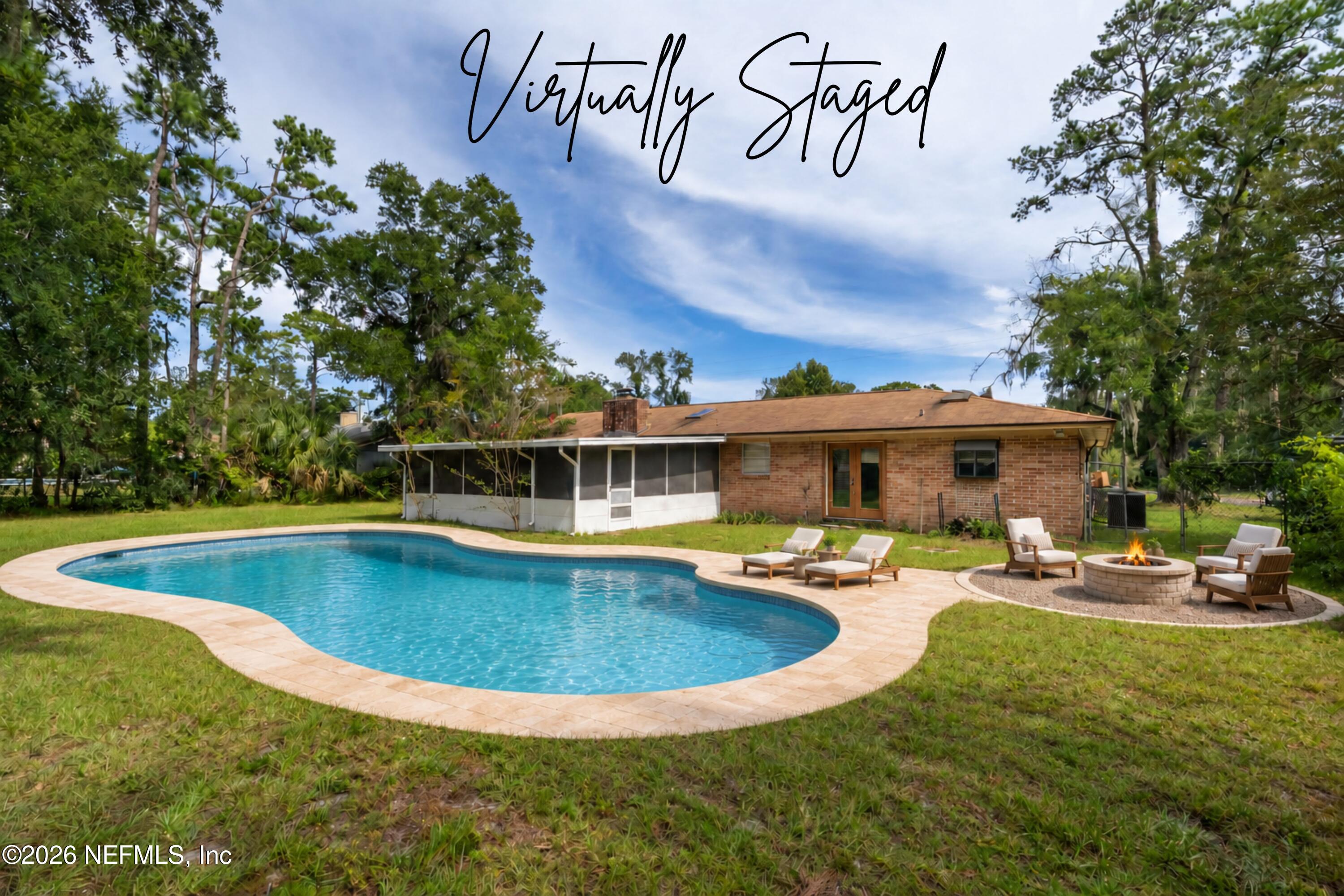 Backyard pool and brick home with a screened patio, lounge chairs, and a fire pit.