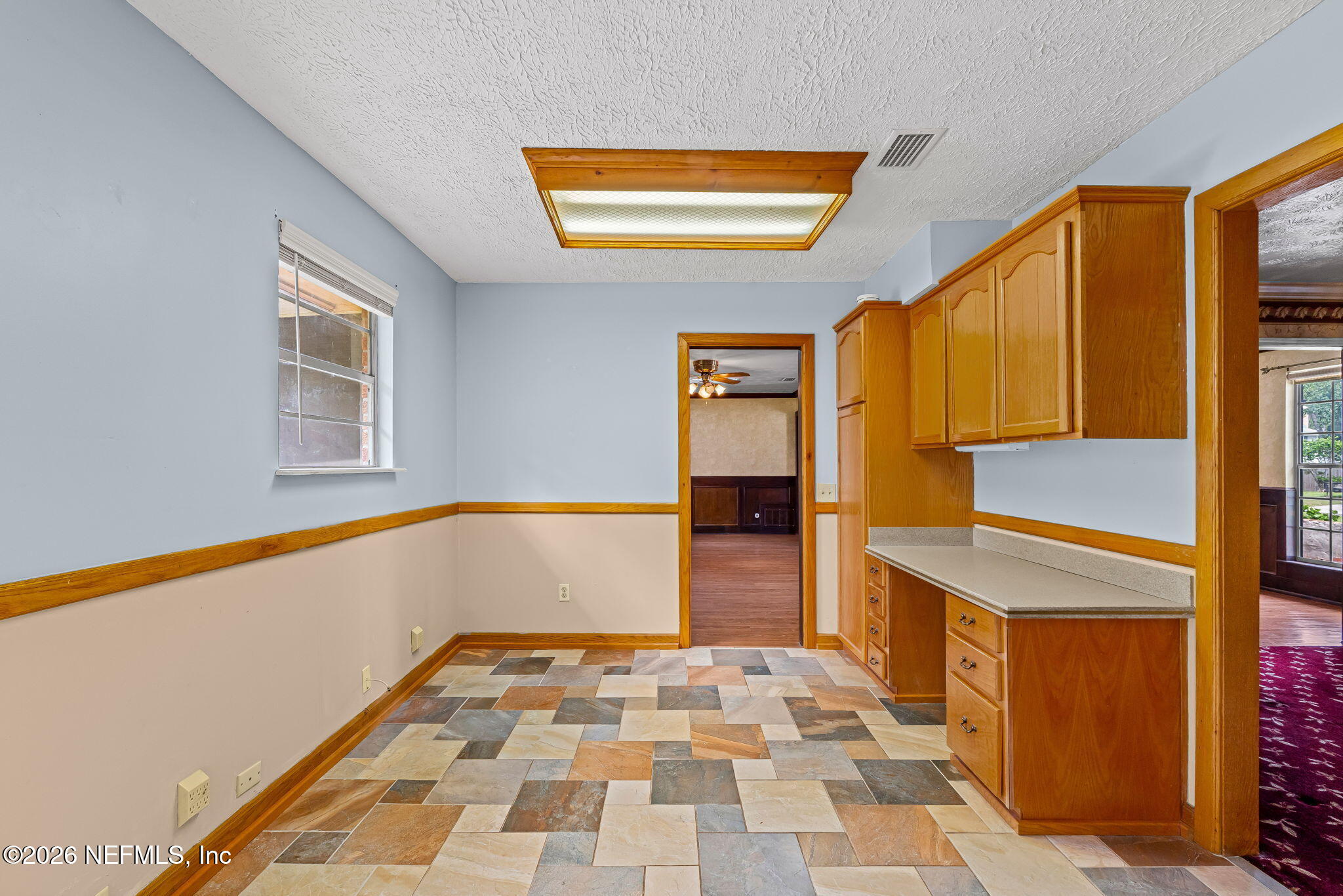 Kitchen with multicolored tile flooring, honey-toned cabinets, and a built-in countertop.